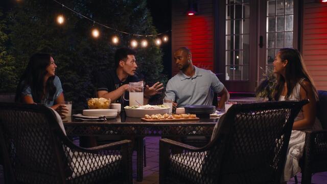 Group having dinner on patio with string and smart lights