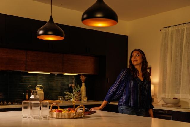 Woman in warmly lit kitchen with two pendant lights